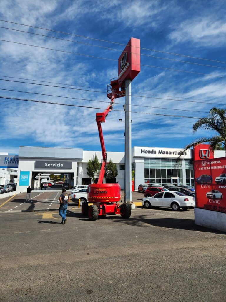 Plataforma de elevacion roja de brazo en una zona pública al lado de un cartel